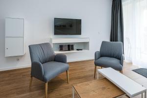 ein Wohnzimmer mit 2 Stühlen und einem TV in der Unterkunft Deichhäuser Anna Küste Deichhäuser Anna Küste 8-20 in Bensersiel