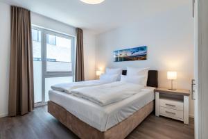 ein weißes Schlafzimmer mit einem großen Bett und einem Fenster in der Unterkunft Aparthotel Ostseeallee Aparthotel Ostseeallee 2-12 in Boltenhagen