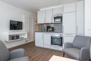 a kitchen with white cabinets and two chairs at Deichhäuser Anna Küste Deichhäuser Anna Küste 8-33 in Bensersiel