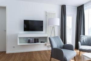 ein Wohnzimmer mit einem TV und 2 Stühlen in der Unterkunft Deichhäuser Anna Küste Deichhäuser Anna Küste 8-34 in Bensersiel