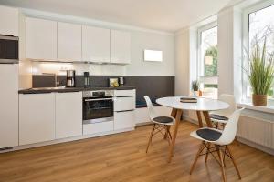 ヘリングスドルフにあるStrand-Park Strand-Park 204の白いキャビネット、テーブルと椅子付きのキッチンが備わります。