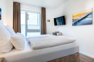 un letto bianco con cuscini bianchi in una camera da letto di Aparthotel Ostseeallee Aparthotel Ostseeallee 4-31 a Boltenhagen