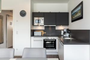 een keuken met zwart-witte kasten en apparaten bij Aparthotel Ostseeallee Aparthotel Ostseeallee 2-16 in Boltenhagen