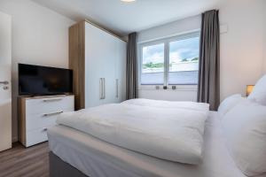 a white bedroom with a large bed and a tv at Aparthotel Ostseeallee Aparthotel Ostseeallee 2-16 in Boltenhagen