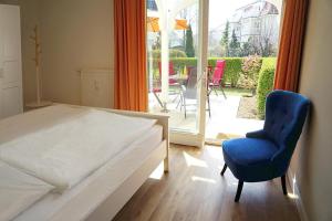 1 Schlafzimmer mit einem Bett und einem blauen Stuhl sowie einer Terrasse in der Unterkunft Apartment-Residenz Ostseestrand Apartment-Residenz Ostseestrand 11 in Kühlungsborn