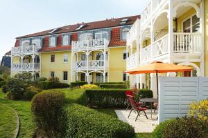ein gelbes Gebäude mit einem Regenschirm, einem Tisch und Stühlen in der Unterkunft Apartment-Residenz Ostseestrand Apartment-Residenz Ostseestrand 11 in Kühlungsborn