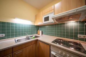 eine Küche mit grünen gefliesten Wänden und einem Waschbecken in der Unterkunft Hus Inselkieker Hus Inselkieker 216 in Schillig
