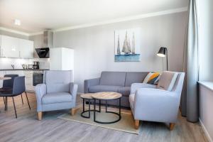 ein Wohnzimmer mit einer Couch und zwei Stühlen und einem Tisch in der Unterkunft Godewindpark Travemünde Godewindpark Travemünde 1-07 in Travemünde + 7 Fotos