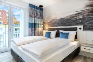 ein Schlafzimmer mit einem großen weißen Bett mit blauen Kissen in der Unterkunft Apartmentanlage Meerblickvilla Apartmentanlage Meerblickvilla 2-18 in Großenbrode