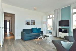 Una sala de estar con un sofá azul y un televisor en Aparthotel Anna Düne Aparthotel Anna Düne 1-18, en Wangerooge