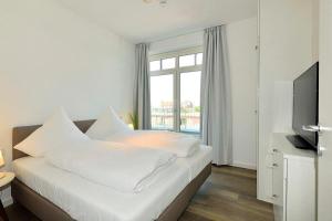Un dormitorio con una cama con sábanas blancas y un televisor. en Aparthotel Anna Düne Aparthotel Anna Düne 1-18, en Wangerooge 6 fotos más