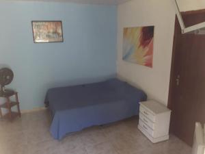 a small bedroom with a blue bed and a chair at casa de Temporada Pimenta Rosa in Saquarema