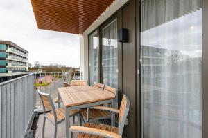 ein Holztisch und Stühle auf einem Balkon in der Unterkunft Deichhäuser Anna Küste Deichhäuser Anna Küste 1-30 in Bensersiel