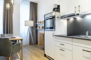 a kitchen with white cabinets and a table and a chair at Ferienapartments am Krusespeicher Ferienapartments am Krusespeicher 2-17 in Wismar +12 photos