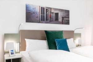 - une chambre avec un lit blanc et un tableau au-dessus dans l'établissement Ferienapartments am Krusespeicher Ferienapartments am Krusespeicher 1-05, à Wismar