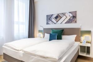 ein Schlafzimmer mit einem Bett mit weißen Laken und blauen Kissen in der Unterkunft Ferienapartments am Krusespeicher Ferienapartments am Krusespeicher 2-18 in Wismar