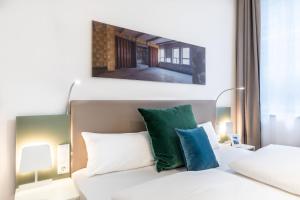 Schlafzimmer mit einem Bett mit grünen und weißen Kissen in der Unterkunft Ferienapartments am Krusespeicher Ferienapartments am Krusespeicher 3-30 in Wismar