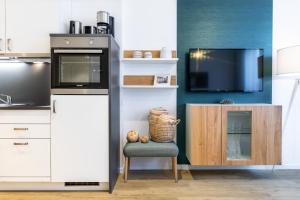 a kitchen with a refrigerator and a chair and a tv at Ferienapartments am Krusespeicher Ferienapartments am Krusespeicher 3-34 in Wismar