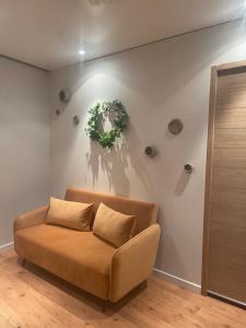 a couch in a living room with a wreath on the wall at Casa Jaubertie - Appartement cosy et chaleureux refait à neuf - HYPER CENTRE BRIVE in Brive-la-Gaillarde