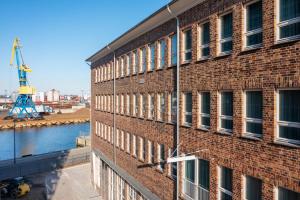 a brick building with a crane in the background at Ferienapartments am Krusespeicher Ferienapartments am Krusespeicher 3-33 in Wismar