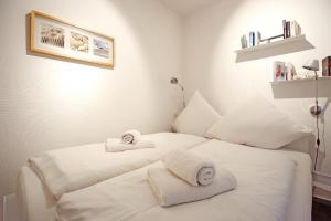 Dos camas blancas en una habitación con toallas. en Haus Panorama Haus Panorama 12 en Wangerooge