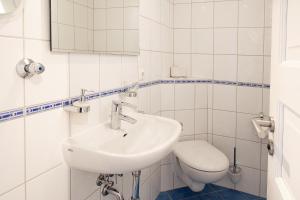 een witte badkamer met een wastafel en een toilet bij Haus Panorama Haus Panorama 12 in Wangerooge +7 foto's