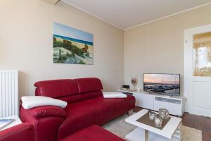 ein Wohnzimmer mit einem roten Sofa und einem Fernseher in der Unterkunft Urlaubsräume am Meer Urlaubsräume am Meer 3-14 in Fulgen