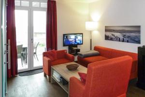ein Wohnzimmer mit 2 orangenen Stühlen und einem TV in der Unterkunft Resort Deichgraf Resort Deichgraf 27-06 in Wremen