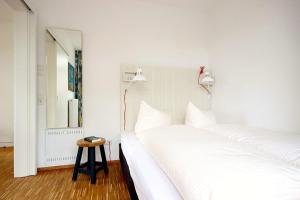 a white bedroom with two beds and a table at Ferienvillen Anna Düne Ferienvillen Anna Düne 1-02 in Wangerooge