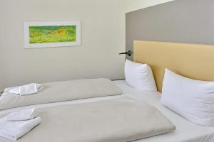 2 Betten in einem Zimmer mit weißer Bettwäsche und Kissen in der Unterkunft Resort Deichgraf Resort Deichgraf 31-08 in Wremen