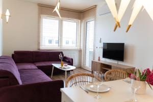 a living room with a purple couch and a tv at Złote Krany Apartament Termalny in Uniejow