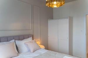 Un dormitorio con una cama con almohadas blancas y una lámpara de araña. en Złote Krany Apartament Termalny, en Uniejów 34 fotos más
