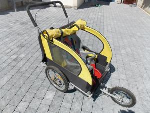 a yellow and black baby cart sitting on a street at Cosy kaz in Bormes-les-Mimosas