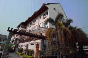 a large white building with palm trees in front of it at Maekhong Delta Boutique Hotel in Mae Sai