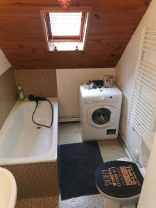 a small bathroom with a tub and a washing machine at Le petit Chalet Luchonnais in Luchon