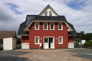 ein rotes Haus mit schwarzem Dach in der Unterkunft Ferienwohnung Strandgut - Kavelweg 9 - Zingst in Zingst
