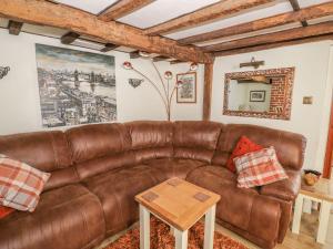 a living room with a brown leather couch at Chapel Cottage in Pewsey