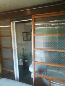 a bathroom with a toilet and a glass door at Hostal La Minga in Chaitén
