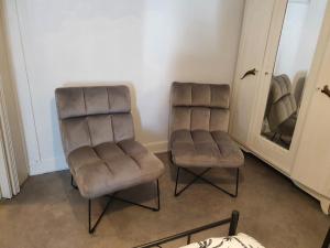 twee bruine stoelen in een kamer met een spiegel bij Meublés HG Bains-les-Bains in Bains-les-Bains