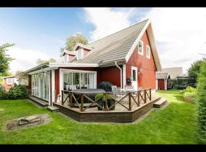 una casa roja con terraza en el patio en Hus i lugnt område, 15 min från Örebro en Vintrosa