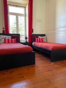 リスボンにあるLisbon Angels Hostelのベッド2台 赤いシーツ、窓が備わるドミトリールームです。