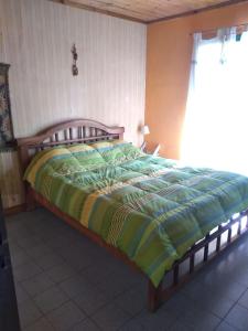 um quarto com uma cama com um edredão verde e amarelo em El sueño del Nono em Potrerillos