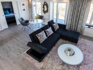 sala de estar con sofá negro y mesa en Penthouse am Südstrand - Kamin, Dachterrasse mit Meerblick und Gasgrill, Luxus-Design-Apartment, 2 Minuten zum Strand, Klimaanlage, en Binz