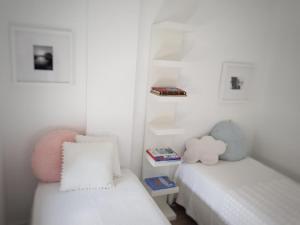 a white bedroom with two beds and a book shelf at Foz Relógio Apartment in Figueira da Foz