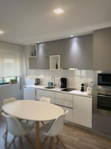 a kitchen with a white table and chairs and a table and a counter at Foz Relógio Apartment in Figueira da Foz