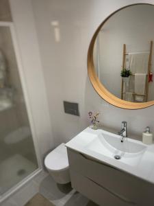 a bathroom with a sink and a toilet and a mirror at Foz Relógio Apartment in Figueira da Foz