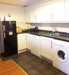 eine Küche mit einem schwarzen Kühlschrank und einem Geschirrspüler in der Unterkunft 4 bedroom home by the sea in Cork
