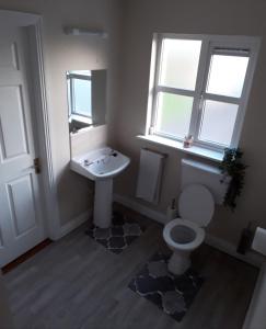 ein Bad mit einem Waschbecken, einem WC und einem Fenster in der Unterkunft 4 bedroom home by the sea in Cork