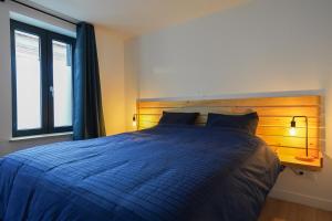 1 dormitorio con cama azul y cabecero de madera en La Villa Bérénice - "Le Duplex" en coeur de ville, en Saint-Amand-les-Eaux