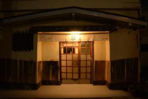 Una porta per un edificio con un orologio sopra di Guesthouse giwa - Vacation STAY 23190v a Mishima